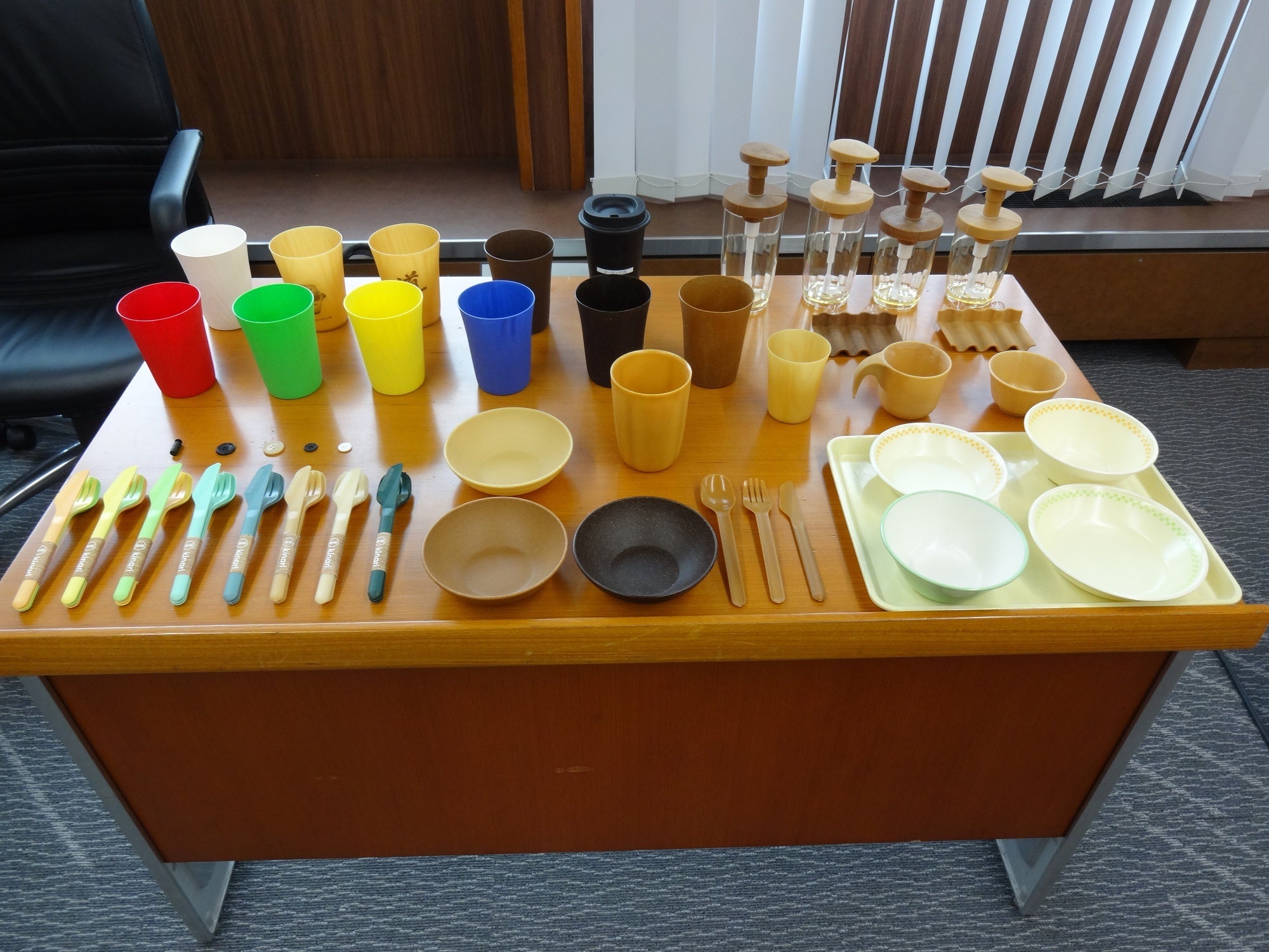 パナソニック独自の「植物繊維を高濃度で複合する最先端技術」により作られたカトラリー見本。右下の食器は、現在の給食食器です。