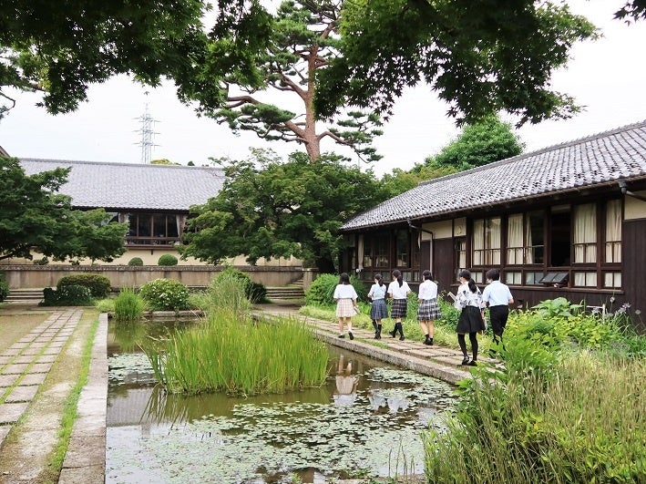 教室棟と池 講堂に向かう生徒たち