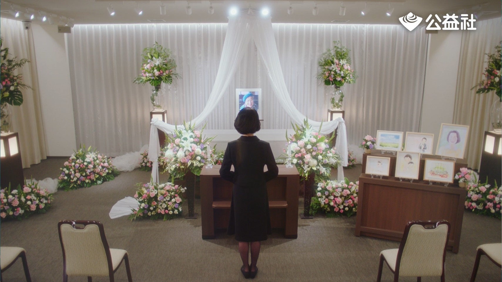 たくさんの絵が飾られている祭壇の前に立つ娘