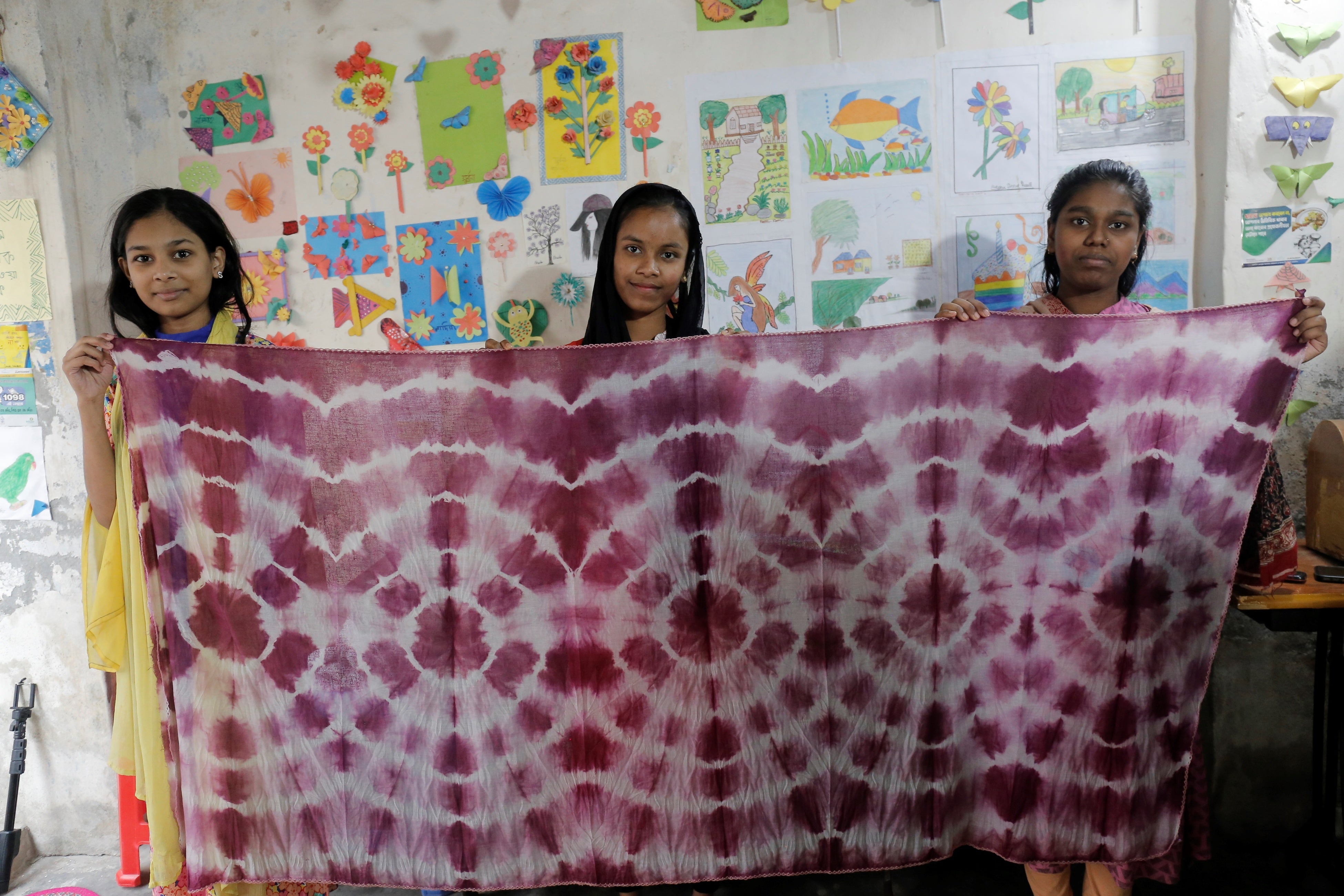 ＜技術研修で藍染を学び完成品のスカーフを掲げる少女たち＞