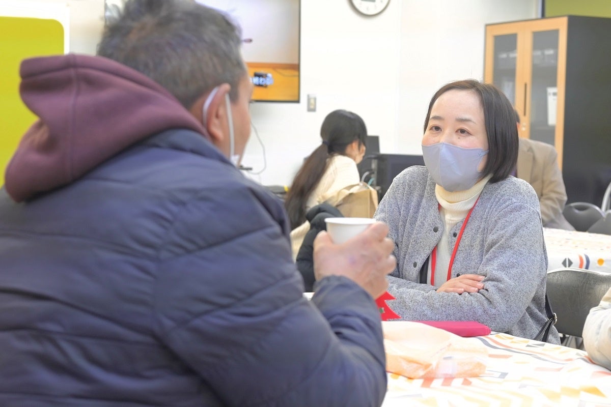 フードパントリー・生活相談会にて利用者の話を聴く職員（右）