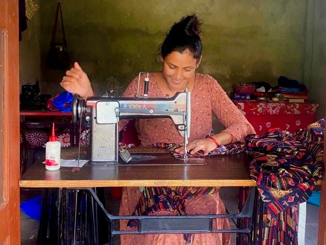 ▲生活改善支援で提供されたミシンを使用する女性