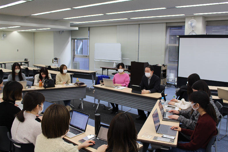 授業の一コマ（左より、NTTデータ経営研究所米倉様、三笠様より指導を受ける学生）