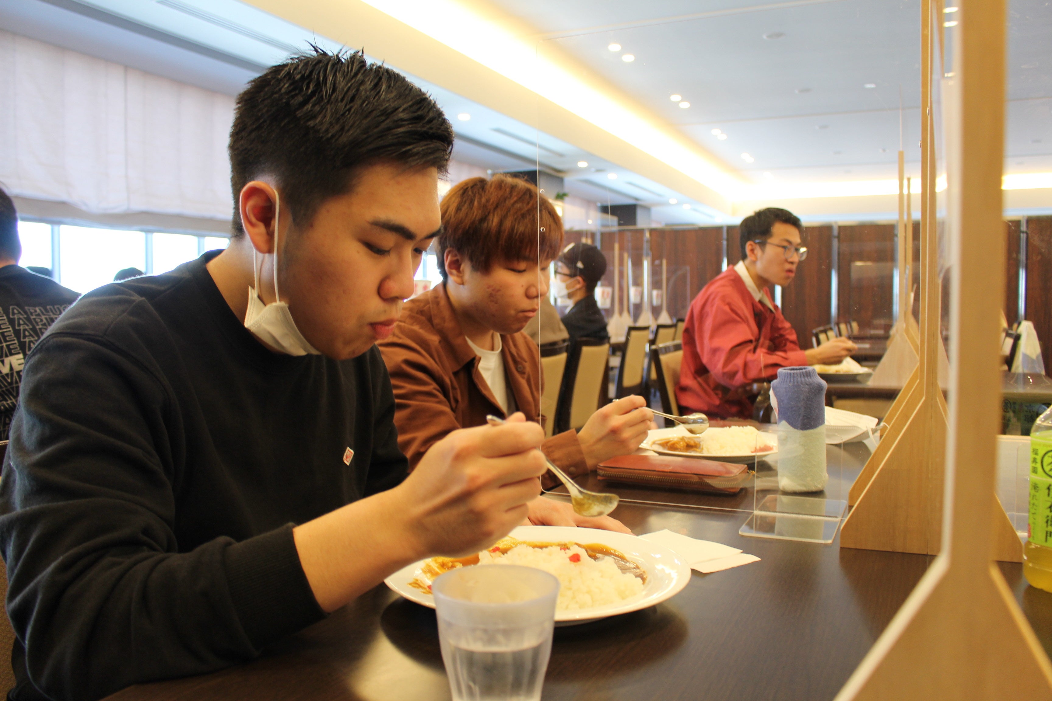 学内向け限定メニューとして人気の高いカレーライスを食べる学生