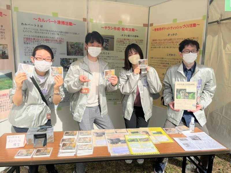 制作した啓発グッズやポスターを手にする本田裕子教授（左）と学生