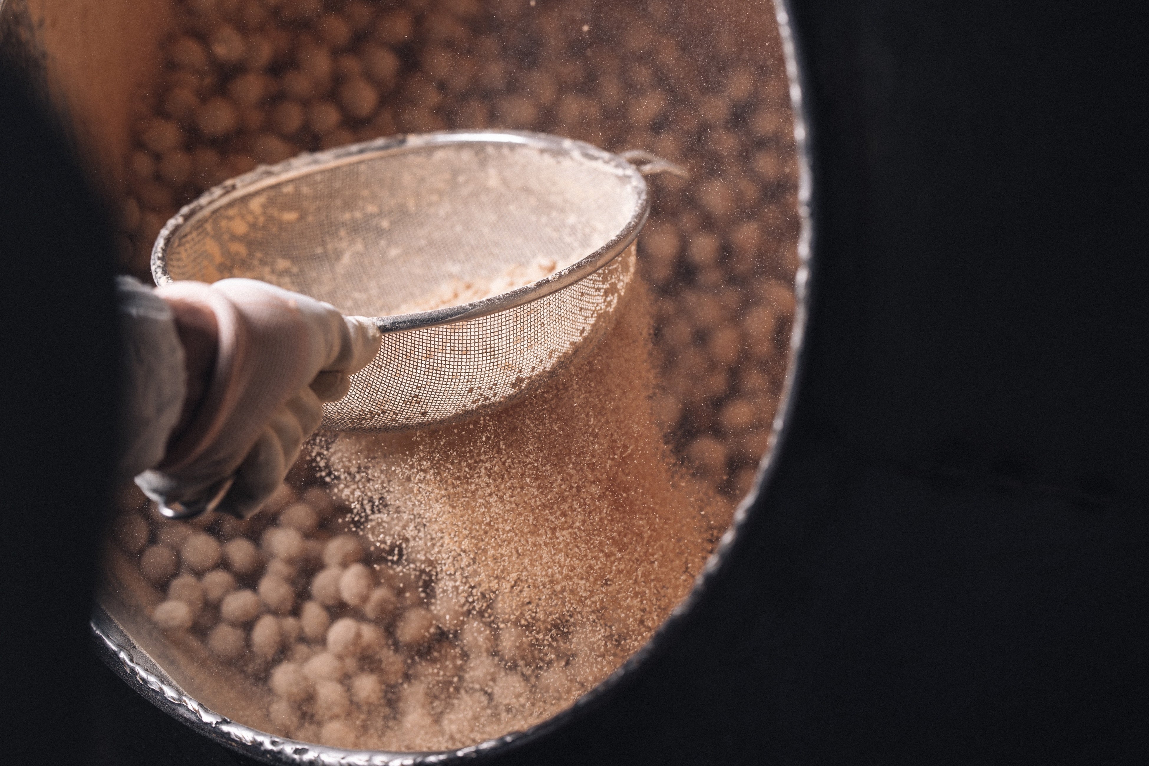 冨士屋製菓本舗の豆菓子を作る際の味付けできな粉をかける様子