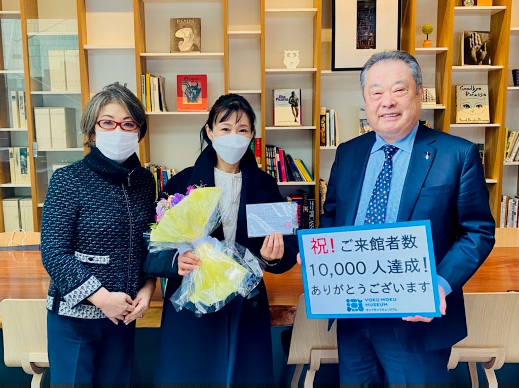 館長の藤縄利康と副館長の藤縄洋子から１万人目の客様へ認定証とともに、花束と記念品の贈呈。お客様からは「今年から美術館めぐりを始めようと思っていて、その第1館目でした！」とコメントを頂きました。※撮影時のみ、館長はマスクを外しております。