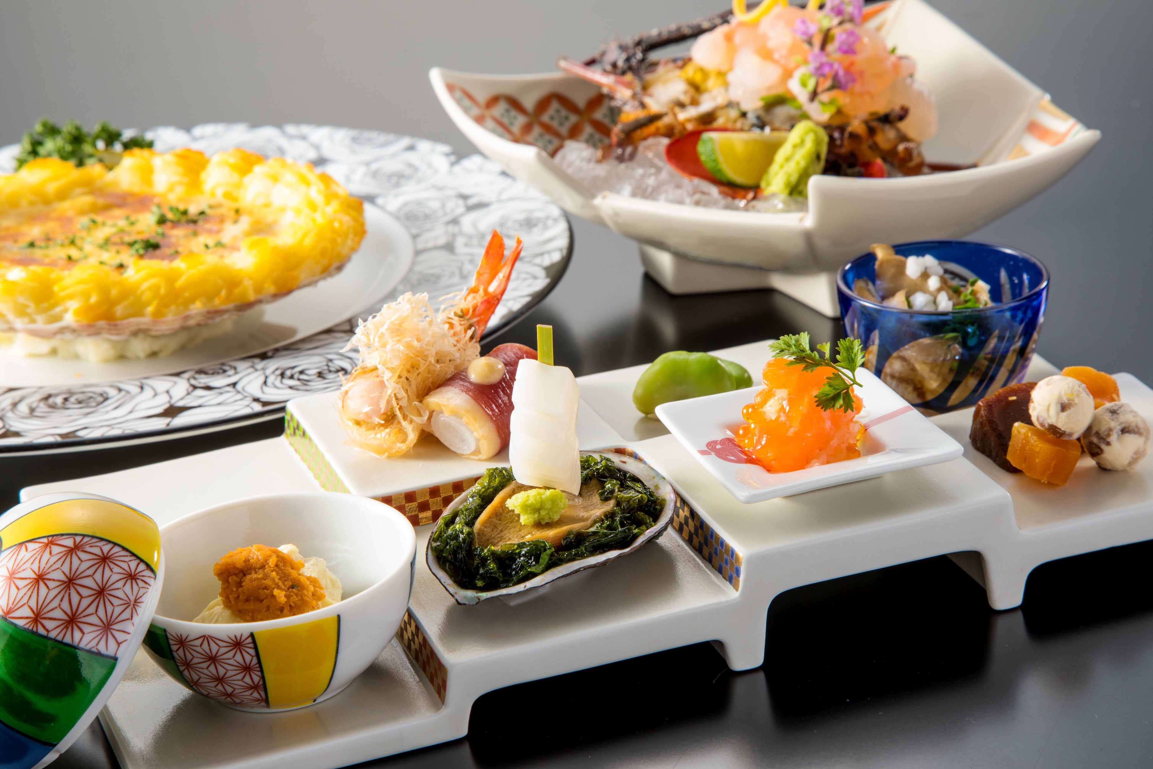 奥左：魚料理「帆立貝のシェルグラタン　フローレンス風」 奥右：「伊勢海老の洗い」、手前：前菜「祝肴・九重」