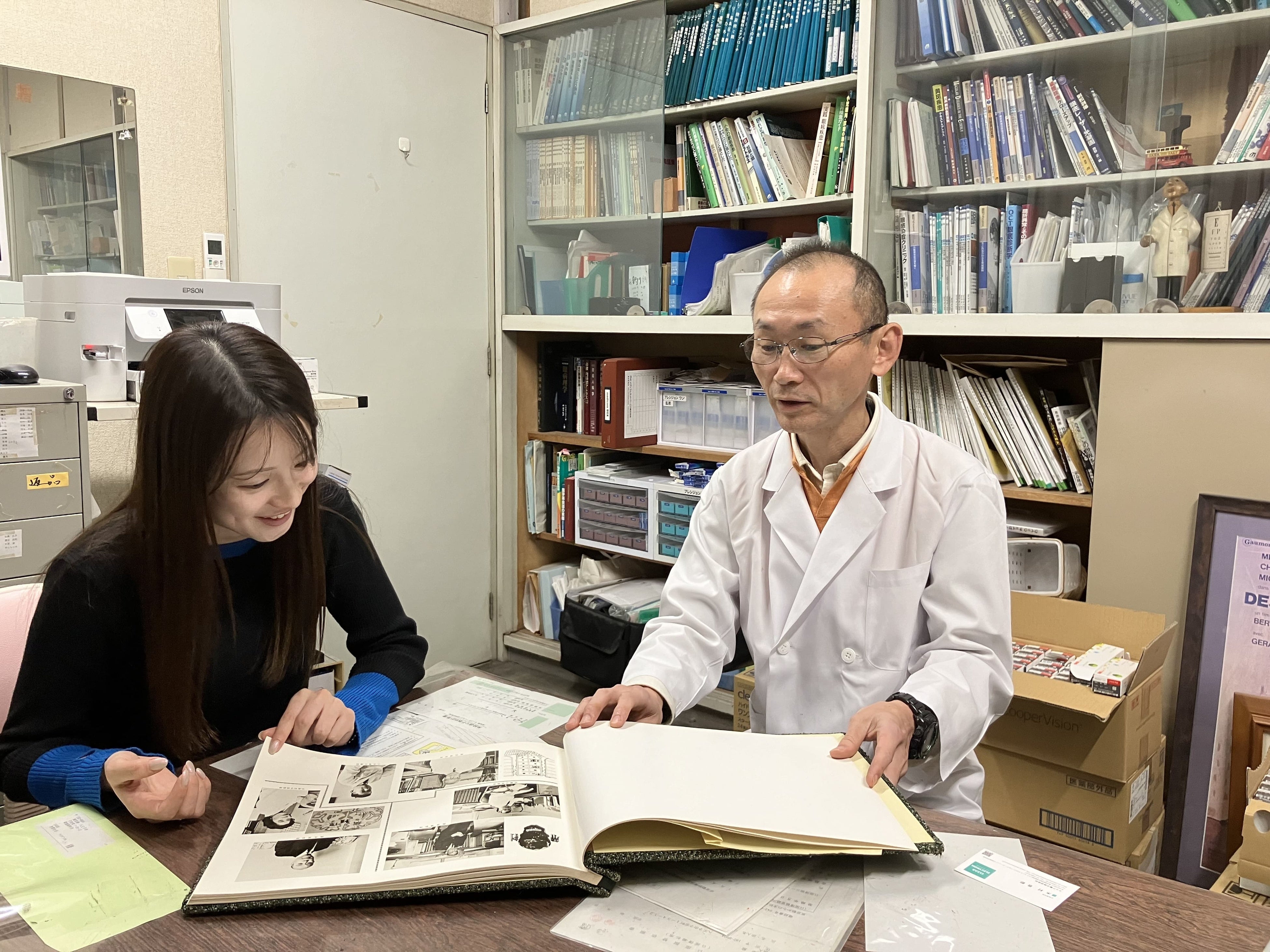 長年続いている菊池眼科医院昔のアルバムを見ながら当時についてお話を聞く様子