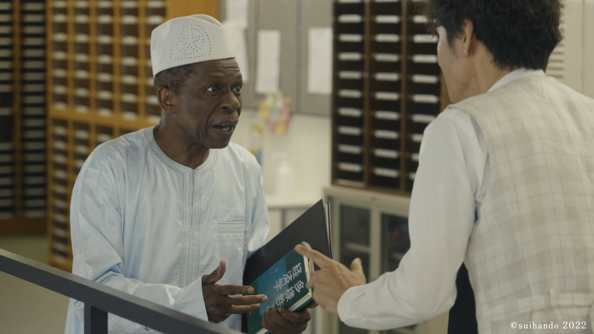 ギニアのコメ料理「リグラ」について激論を交わす国際大学オスマン・サンコン教授役（オスマン・サンコン）と小松沢教授（甲本雅裕）