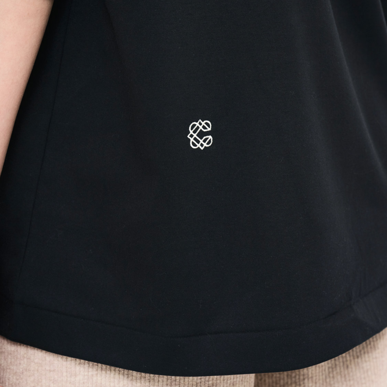 後ろ身頃の左下には刺繍のワンポイント。４つのCで構成されたマークは、Creativity（創造性）、Craftsman(職人）、Customer（お客様）、Circulation(循環）を意味し、この集合体がブランドのDNAで在るということを表しています。