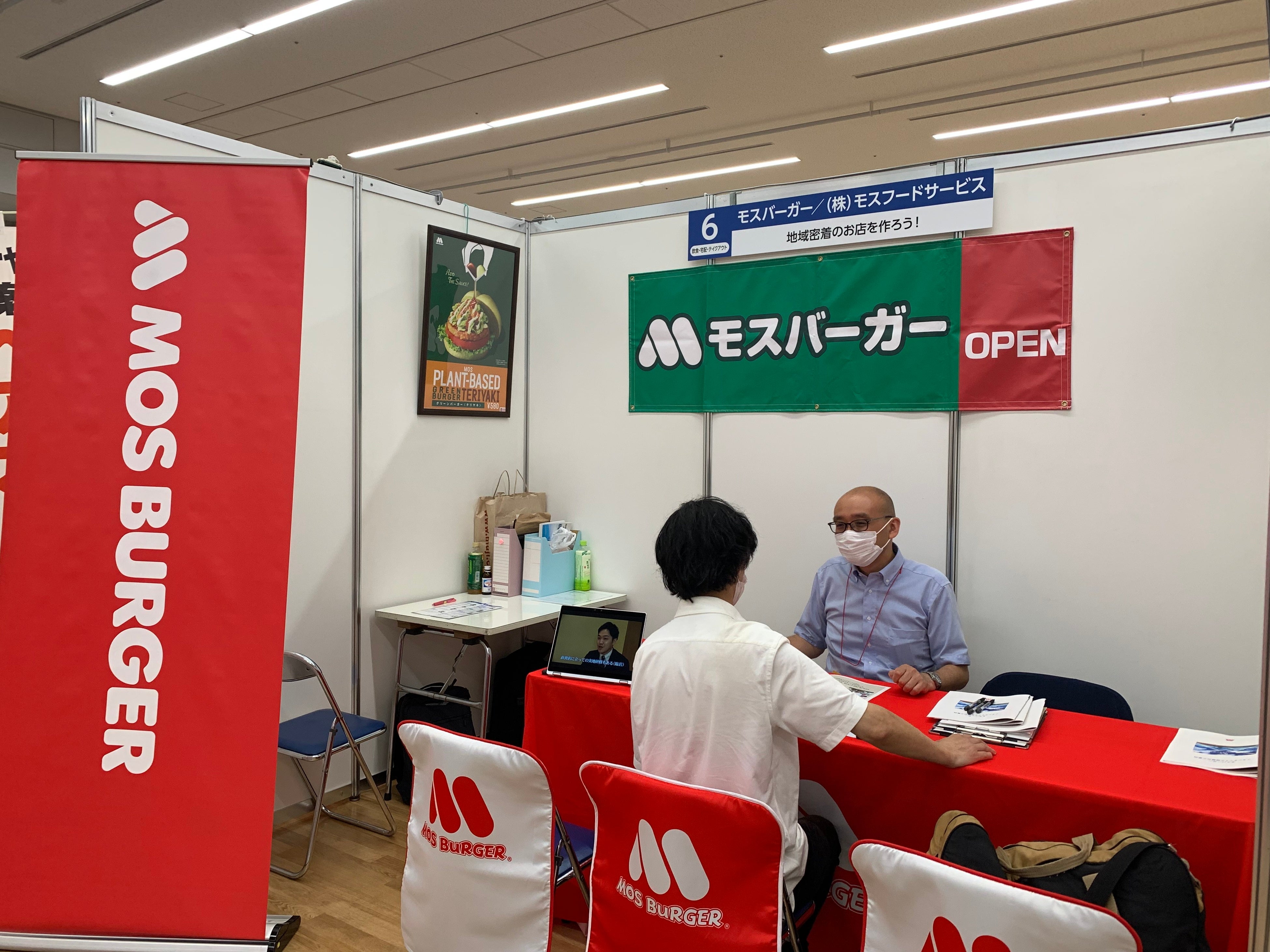 モスバーガー事業について紹介する出展企業 （株式会社モスフードサービス）と説明を聞く来場者