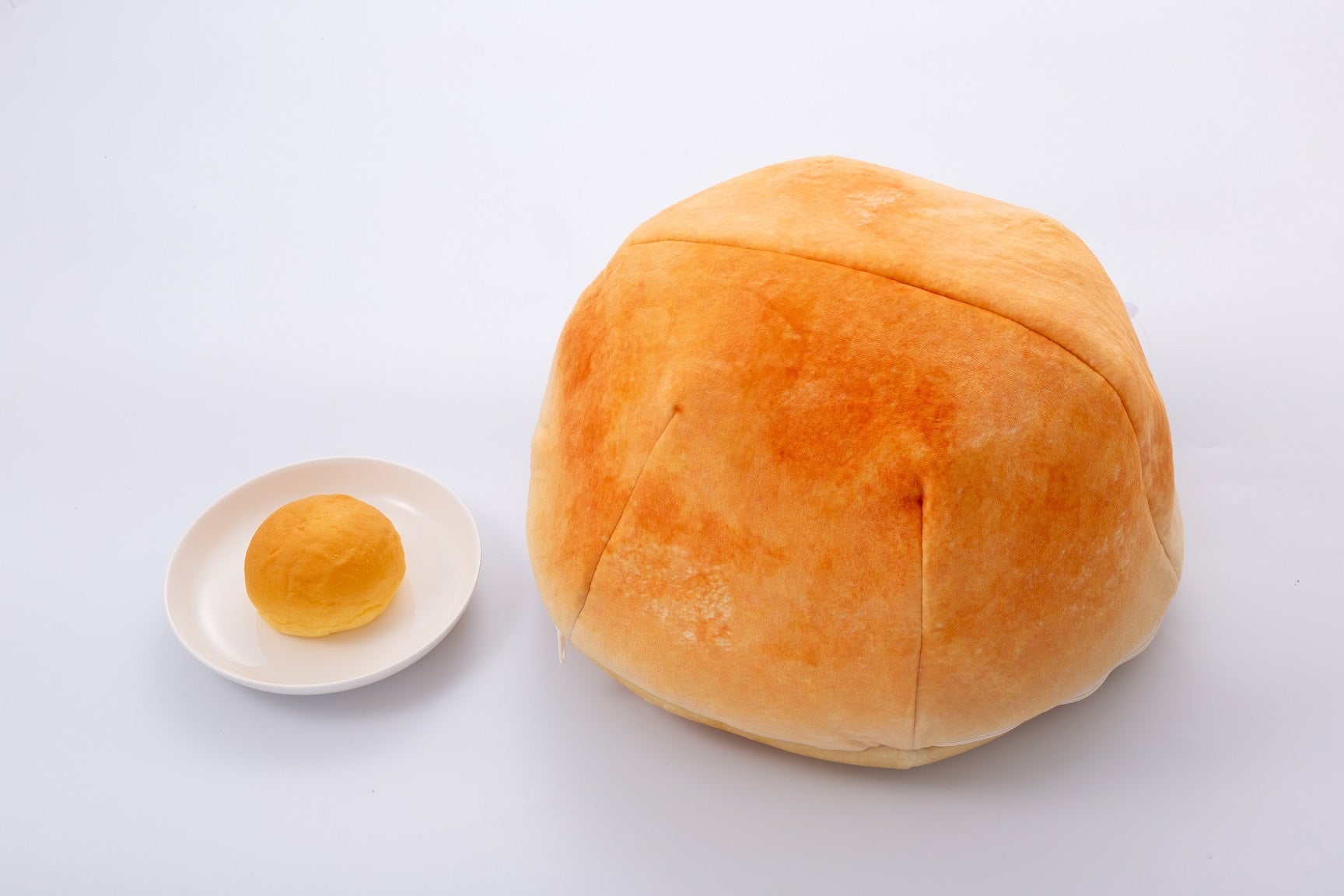 実際のくりーむパン（左）と比較したクッション。手触り良いスムース生地はふんわり柔らかなくりーむパン型ケース。（約30cm）