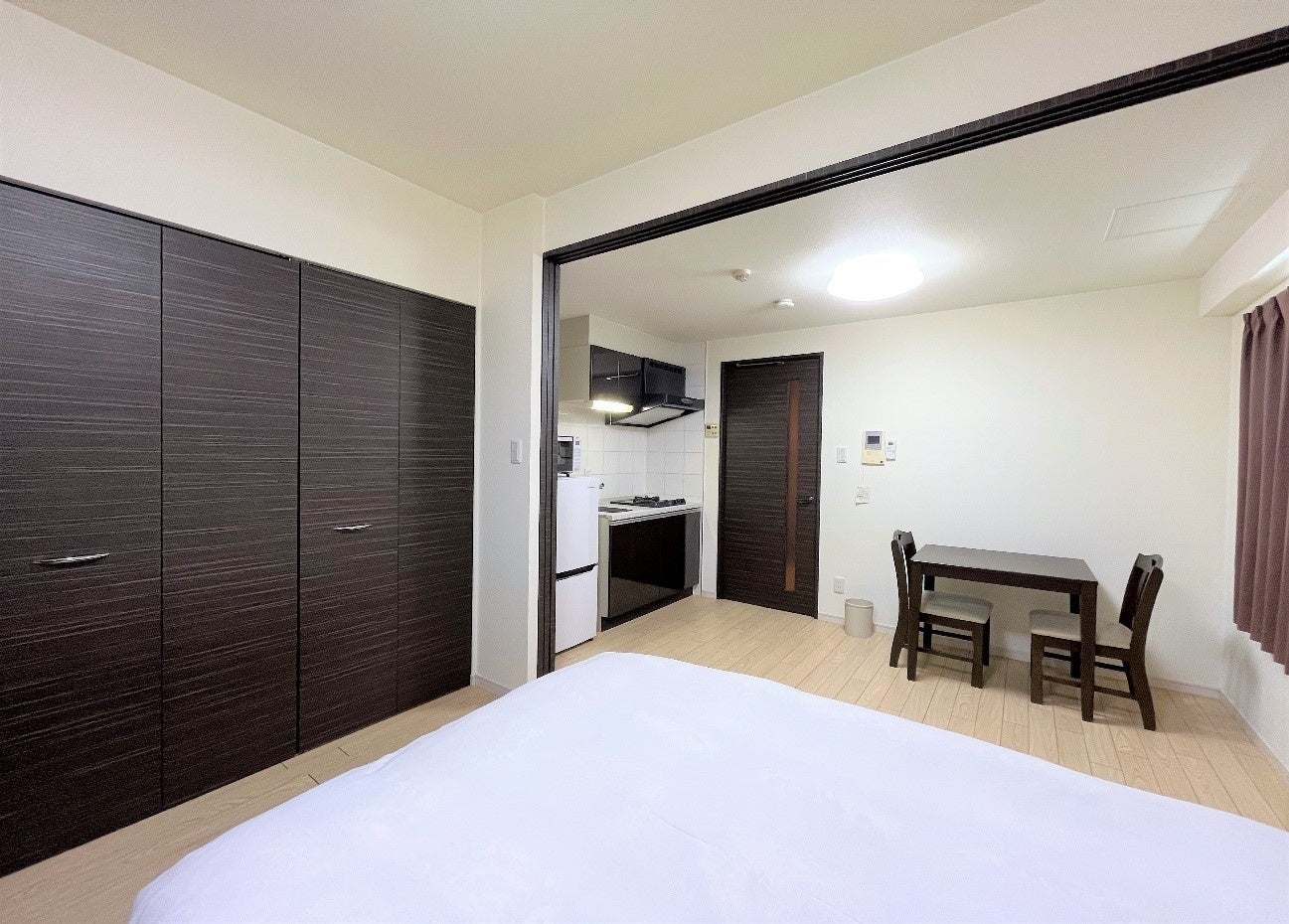 ダブルベッド、ソファ、ダイニングセットを設置した1DKのお部屋