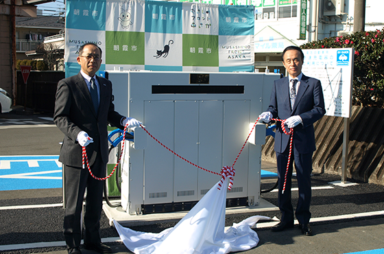 寄贈式で充電器を披露する富岡市長(右)と鈴木社長(左)