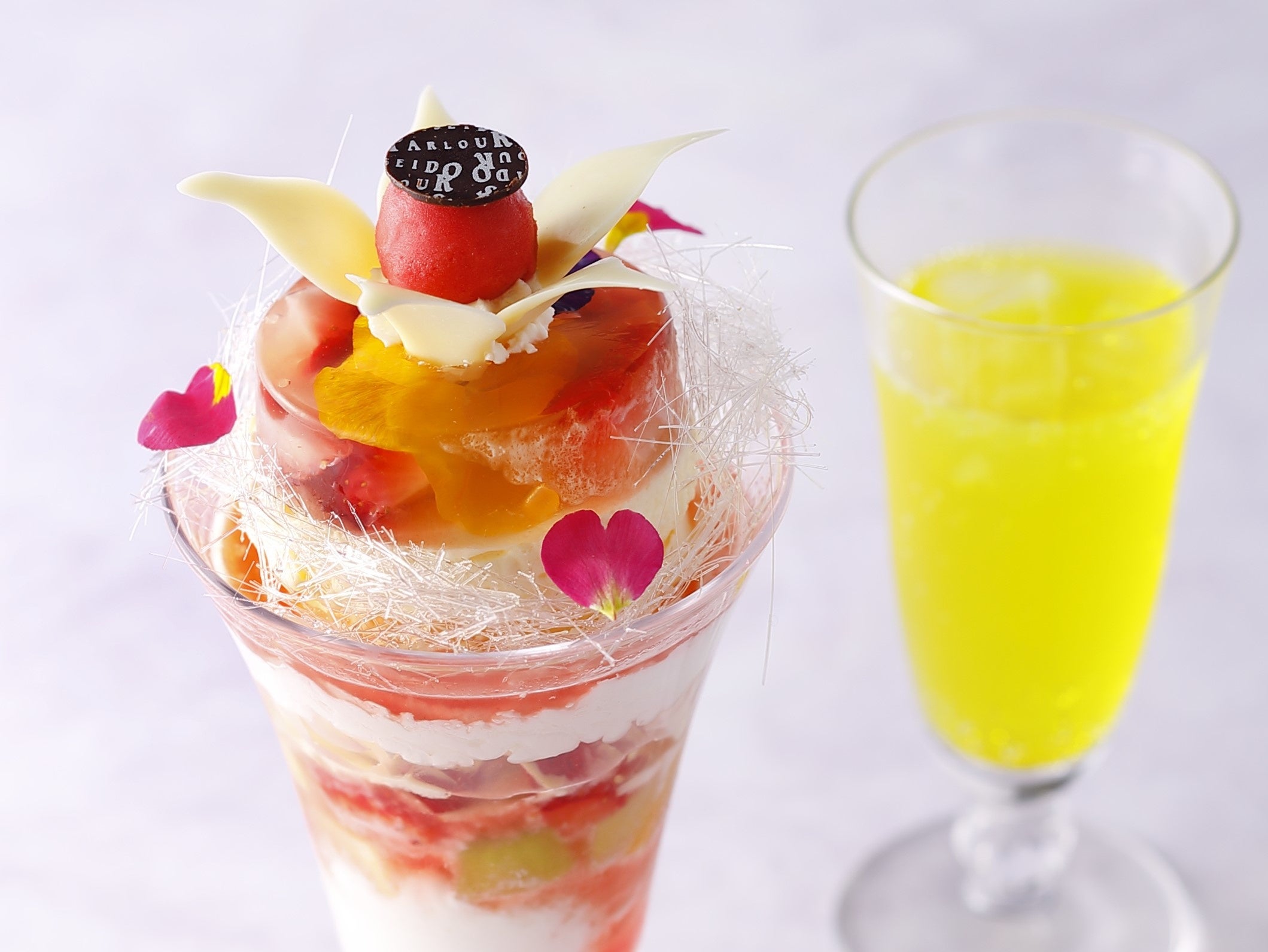 苺とエディブルフラワーをロゼスパークリングワインで閉じ込めたゼリーの上にフランボワーズソルベの花が咲いたような華やかなパフェ