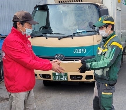 共同配送のイメージ （おむす便スタッフに荷物を受け渡す様子）