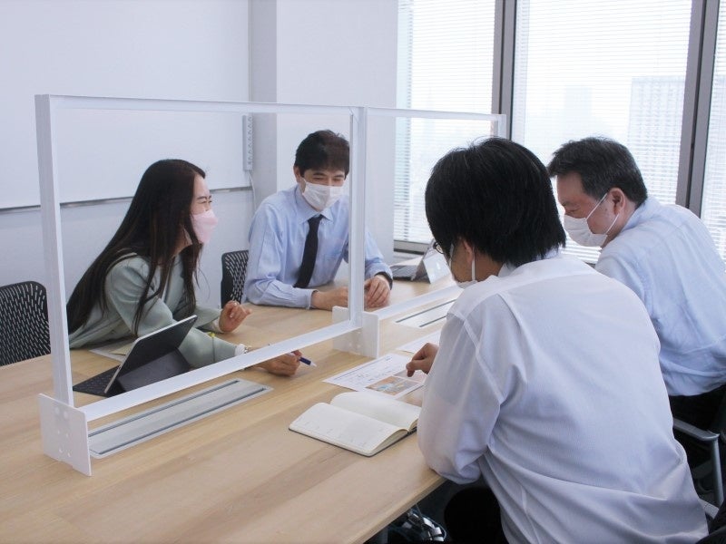 新型コロナウイルス等の感染防止対策として社内に導入した「DNP低反射・低遮音フィルムパーティション」を使って議論する様子 