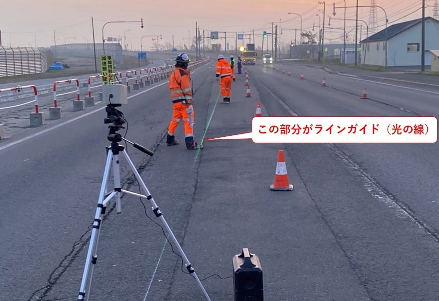 投射したラインガイド（緑の光の線）に沿った区画線塗工作業（施工：北海道技建株式会社）