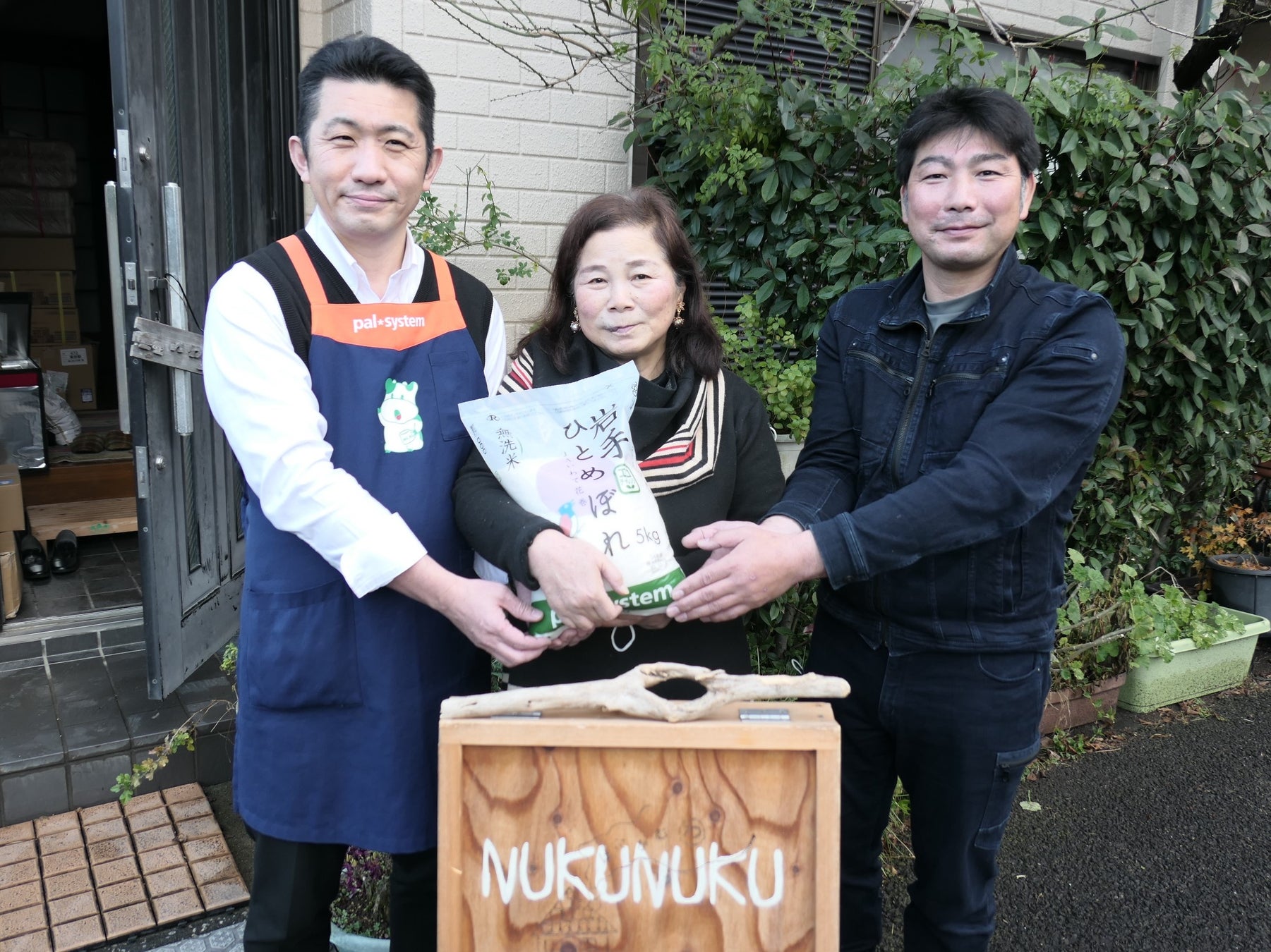 井山さん(中央)を囲み米を手渡す青木さん(右)と増田(左)
