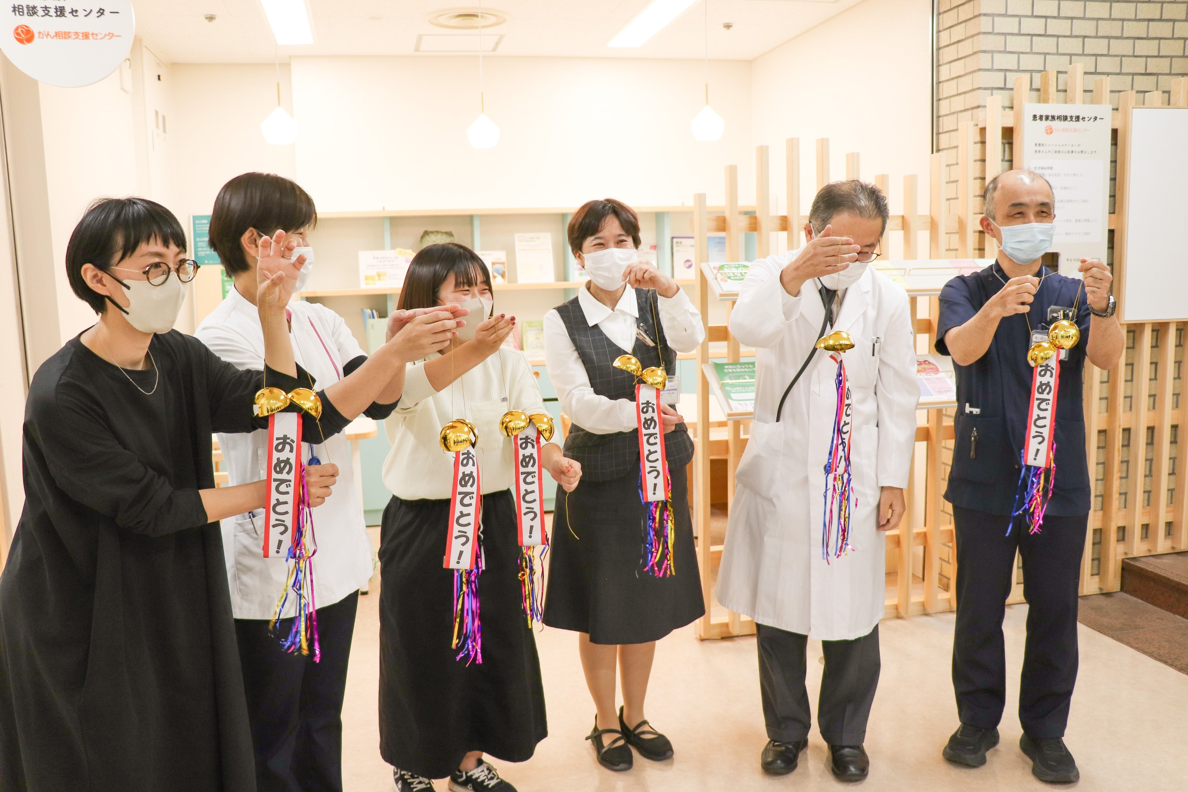 竣工式でくす玉を割り、喜ぶ当院職員とアートコーディネーター