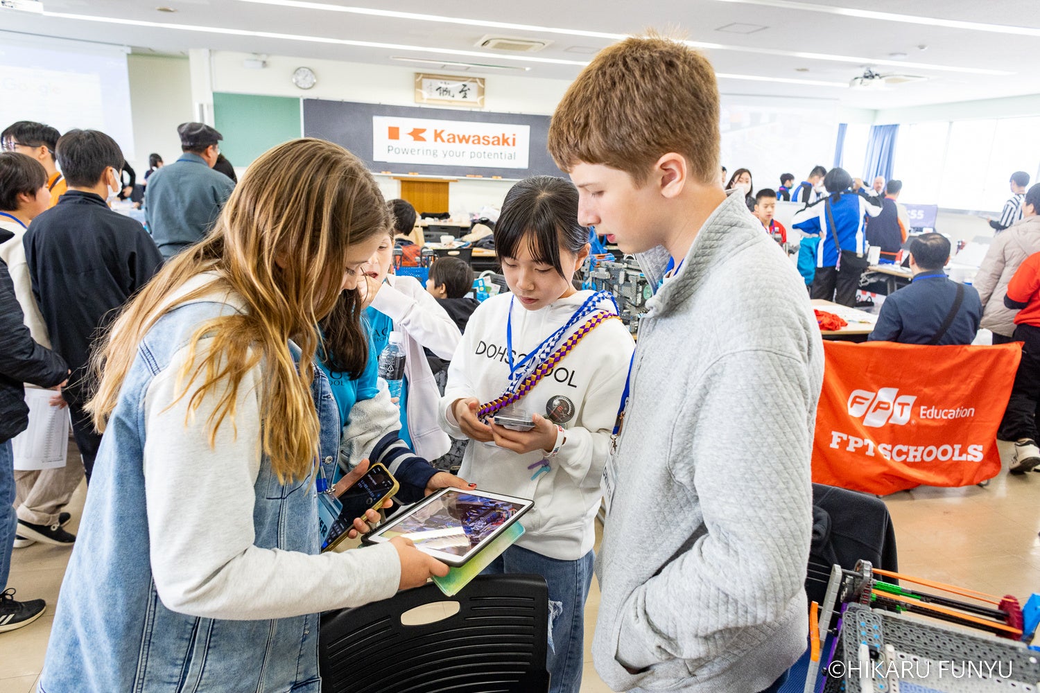 スマートフォンの翻訳アプリと画像を使って作戦会議をする子供達