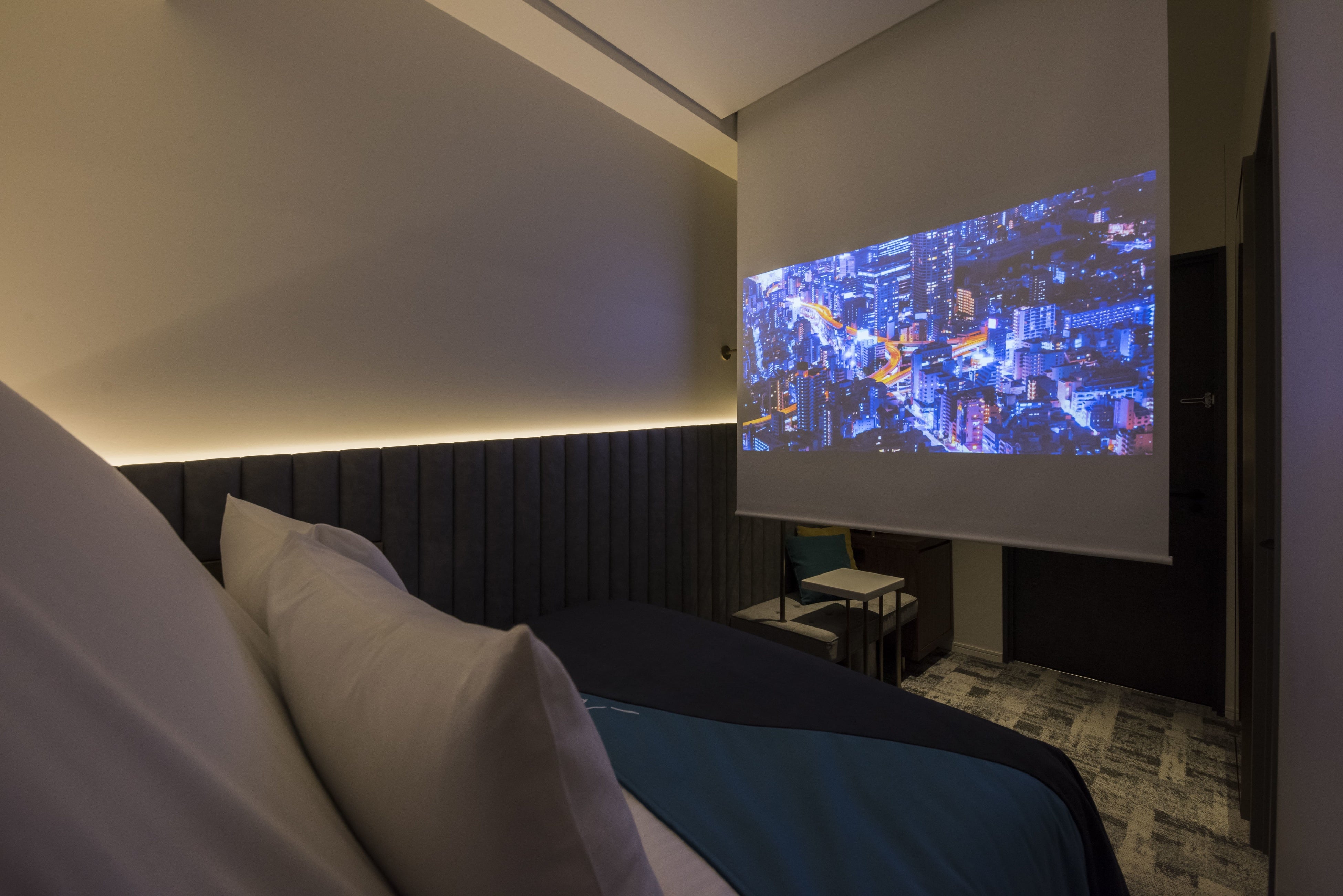 （全室プロジェクター設置。電動スクリーンを下ろすとベッドの前には80インチの大画面。）