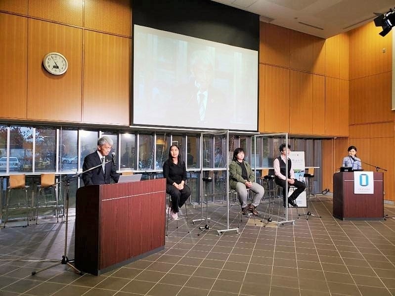 閉講あいさつを行う鈴木孝義副学長と登壇した留学生(司会は、ハルミルザエヴァ サイダ グローバル人材育成院准教授)