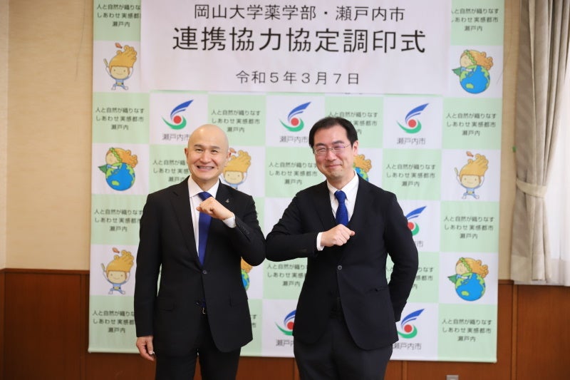 肘タッチする武久市長（左）と狩野学部長（右）