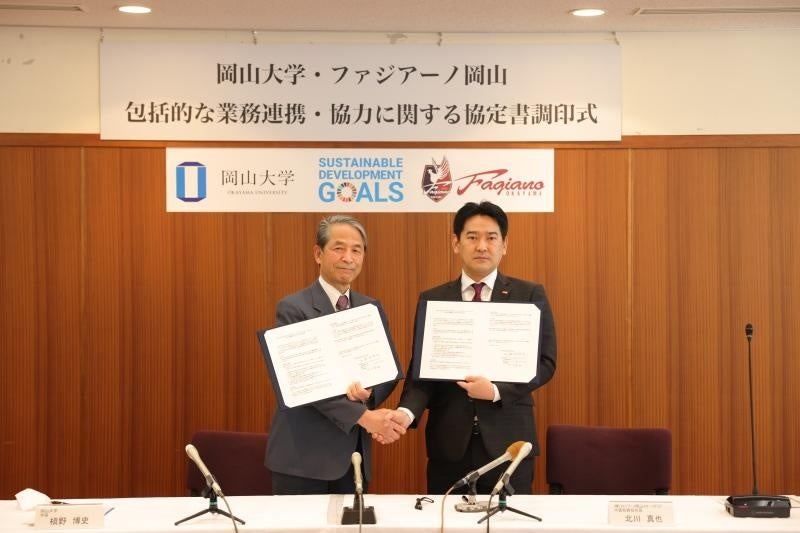 協定書を手に固く握手を交わす北川社長(右)と槇野学長