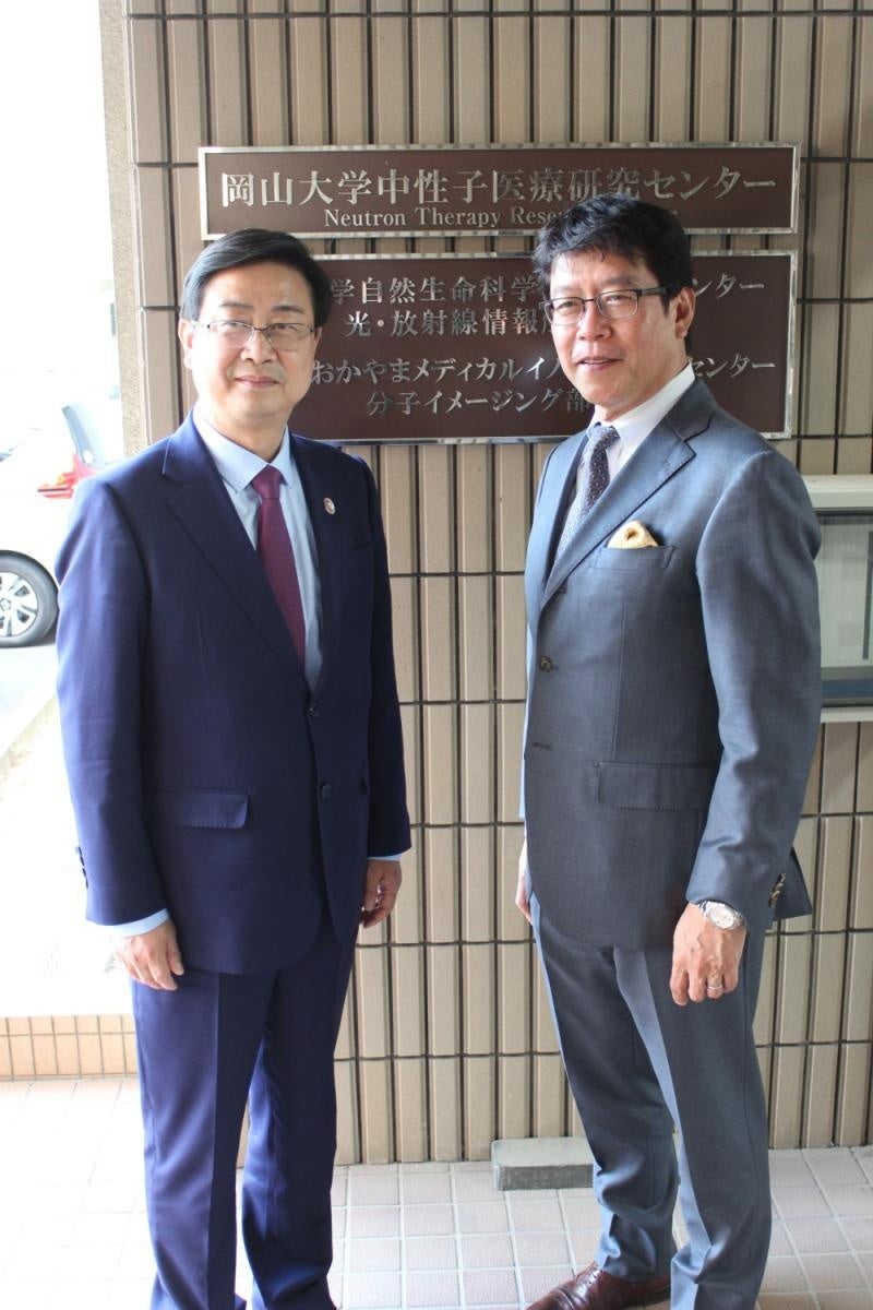 中性子医療研究センターの看板前での劉院長と成瀬副理事・センター長（右）