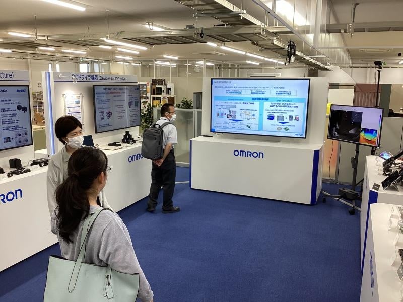 共創エリアにある展示ブースを見学する本学職員ら