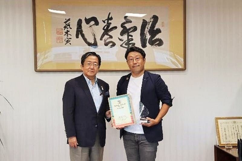 表彰状を手にする高岡准教授(右)と那須学長