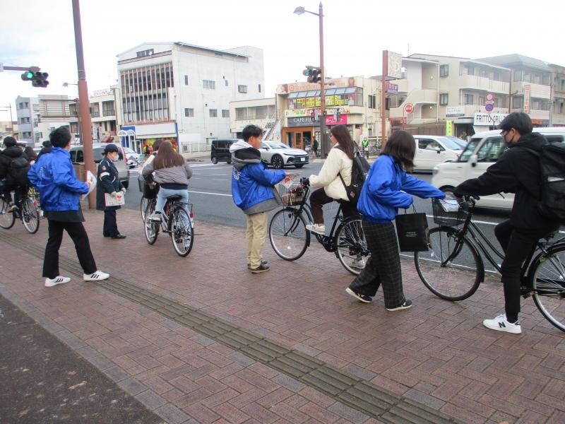 チラシを配布する学生と安全運転を呼びかける警察官
