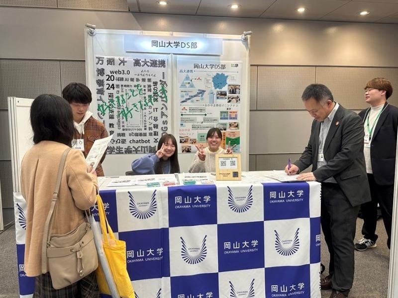 岡山大学データサイエンス部の展示ブースと顧問の野上副理事(右から2人目)