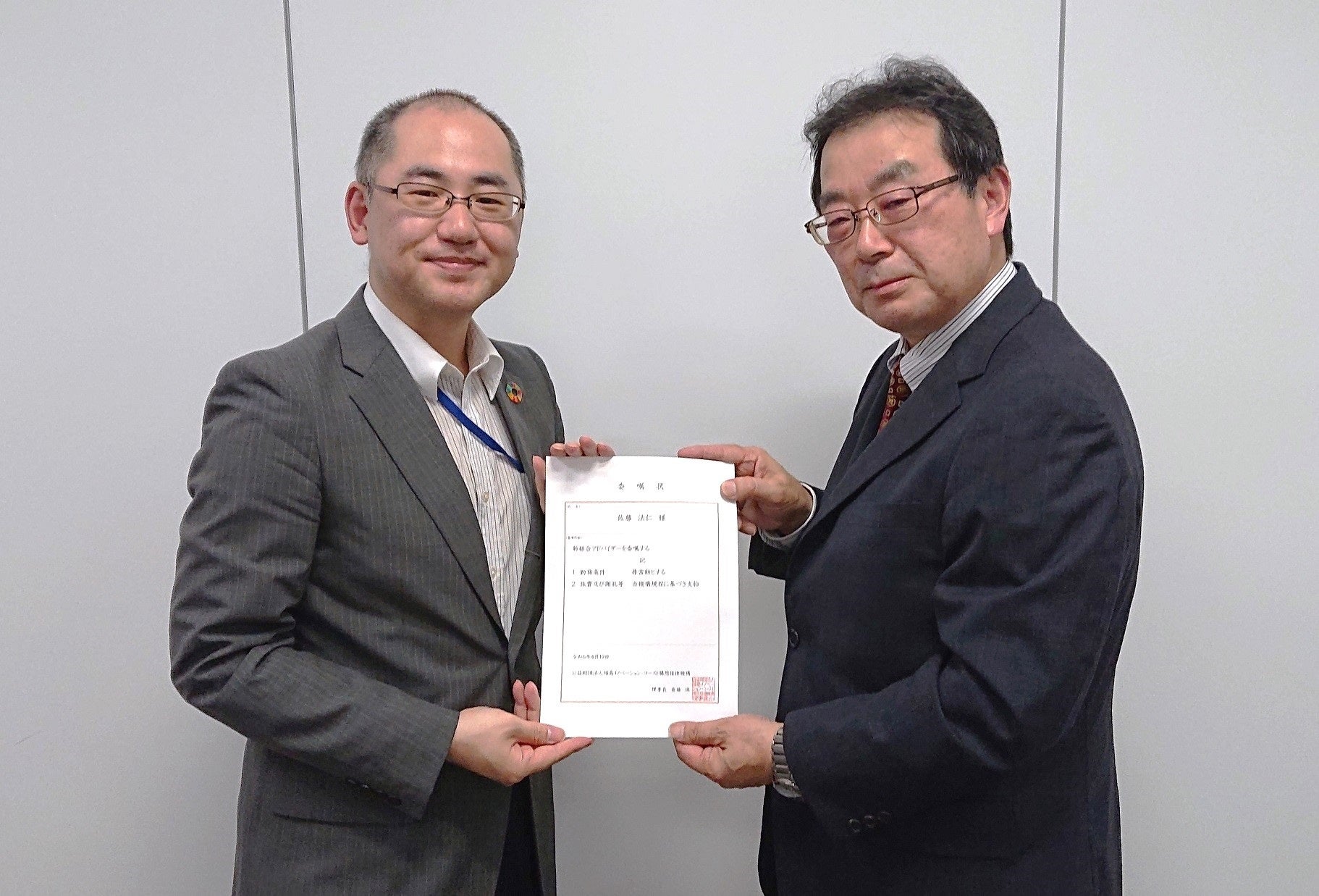 福島イノベ機構の伊藤泰夫理事長補佐からアドバイザー委嘱状を受け取る佐藤法仁副理事・副学長・上級URA(左)