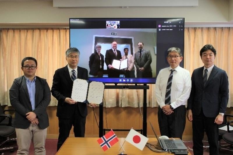 協定書を掲げる髙瀬学部長(左から2人目)とMorten Ørbecck学部長(中央画面、左から2人目)