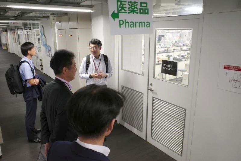 理工学基礎実験室の大規模実験実習についてノウハウを聞く堀課長(写真左奥)ら