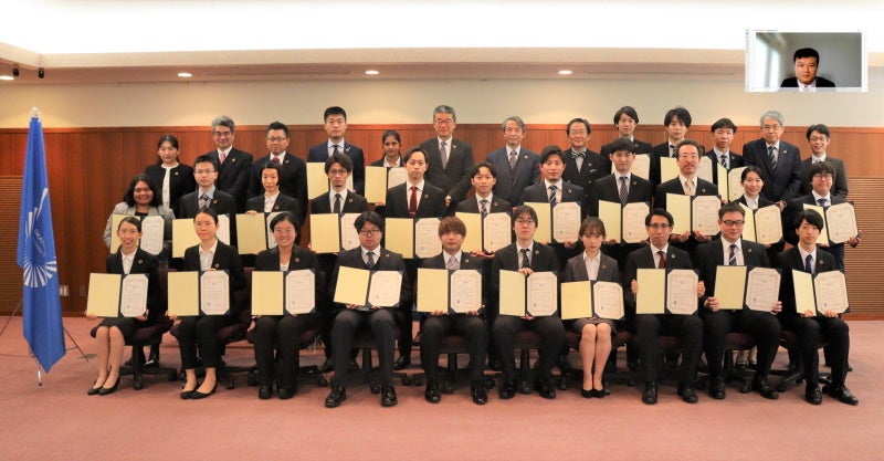 認定者・関係者による記念撮影（前列・中央列：認定者、後列：認定者と関係者（中央が槇野学長）） ※オンライン参加者を加工して追加しています。また、写真撮影時のみマスクを外しました。