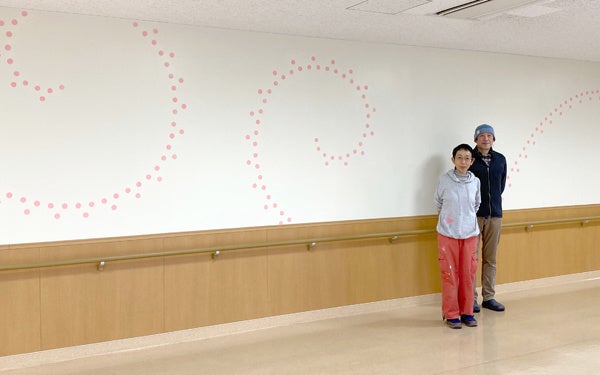 完成したデザインをバックに西山美なコさんと林伸光さん