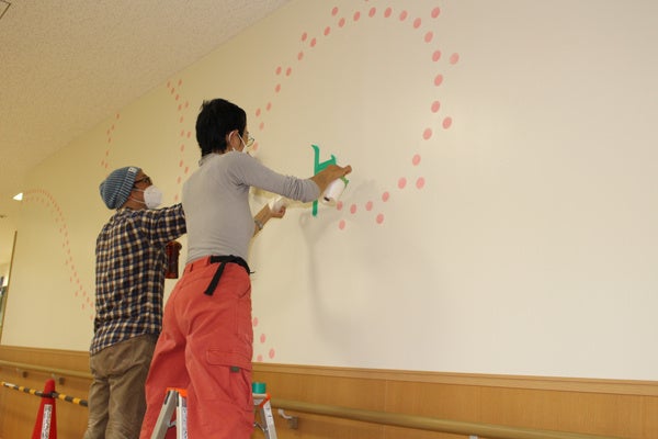 壁面に描画する西山さん（右）とアシスタントの林さん
