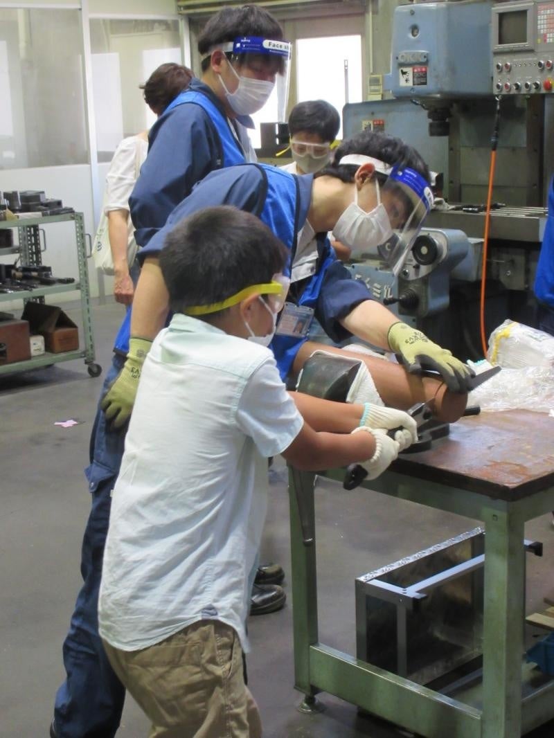 ノコギリを使い、丸太からコースター用の木材を切り分けている様子