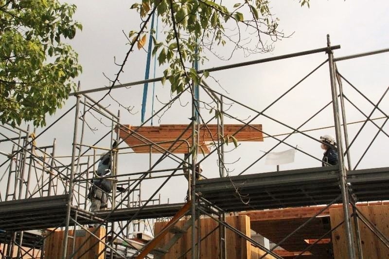 クレーンから吊るされたCLTを設置する様子