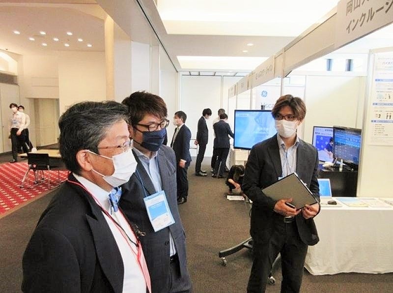 ブースを見学する那須保友理事・副学長(左)