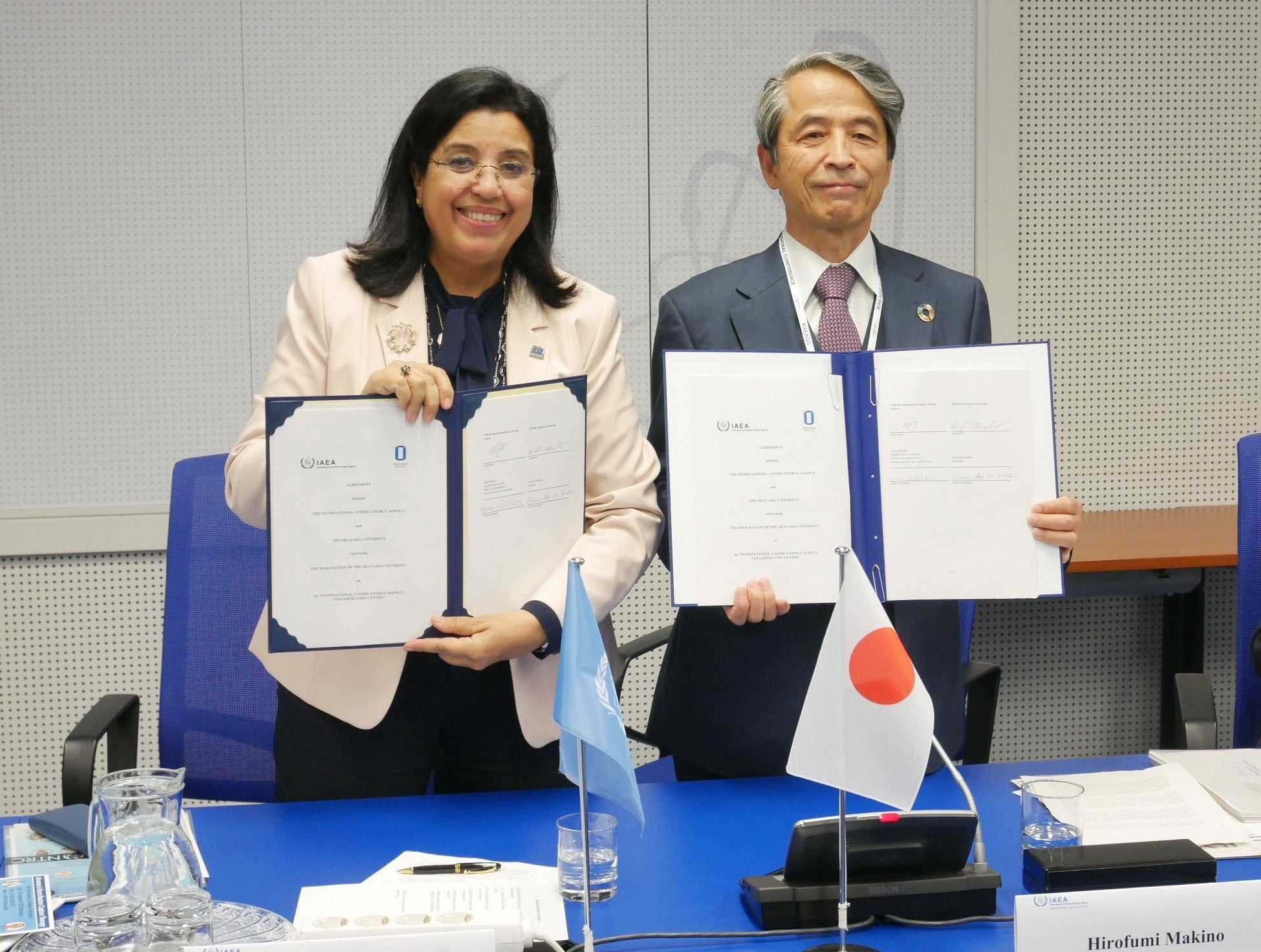 署名した協定書を掲げるナジャト・モクタールIAEA事務次長と槇野博史学長（右）