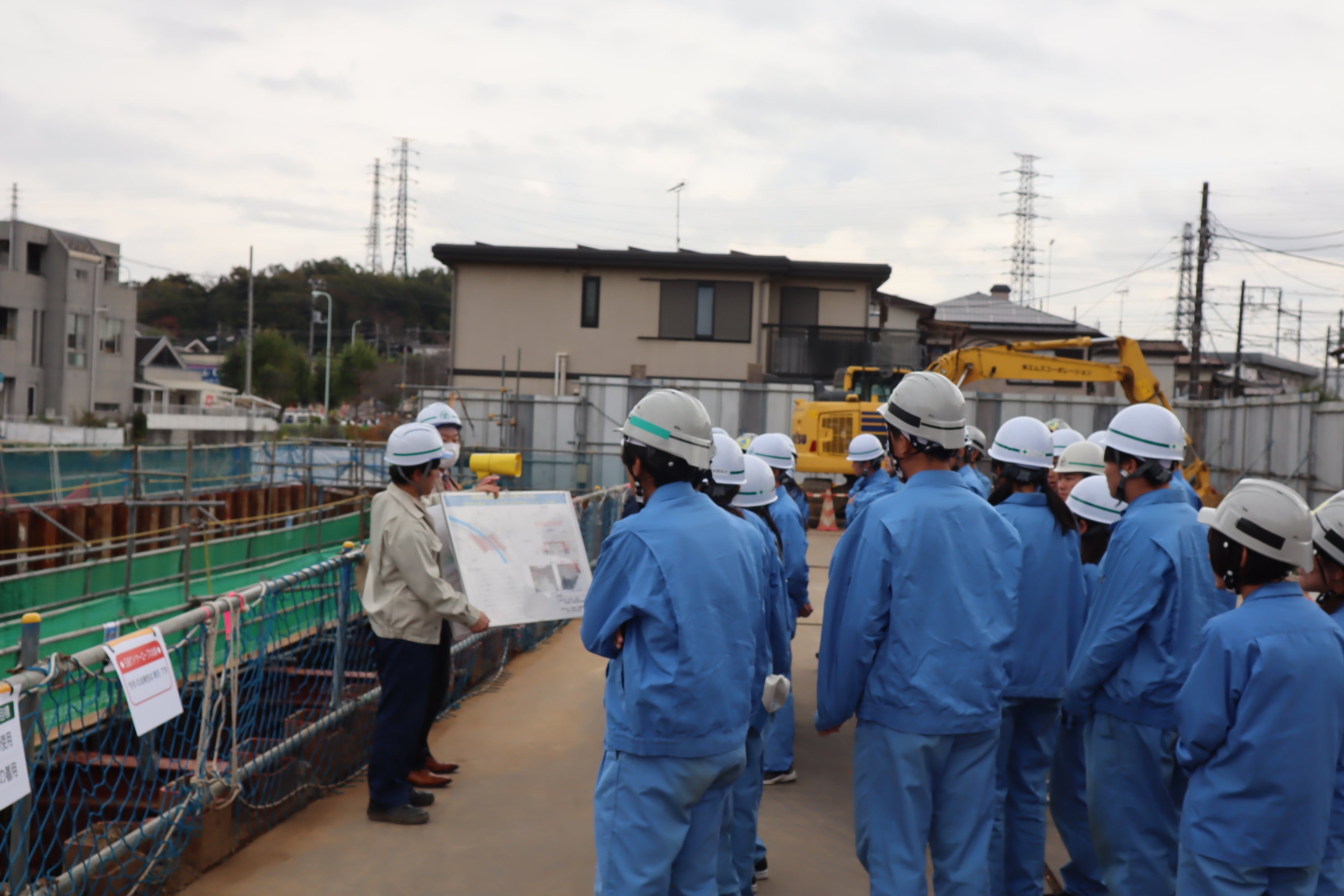 工事の現場で道路整備課職員による説明に耳を傾ける生徒たち