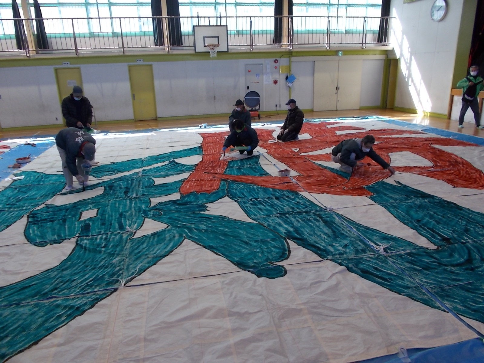 体育館いっぱいに広がる和紙に文字を書いていきます