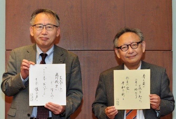 盛田取締役（左）と吉田社長がそれぞれ相手の上の句に下の句を付けて交換しました。