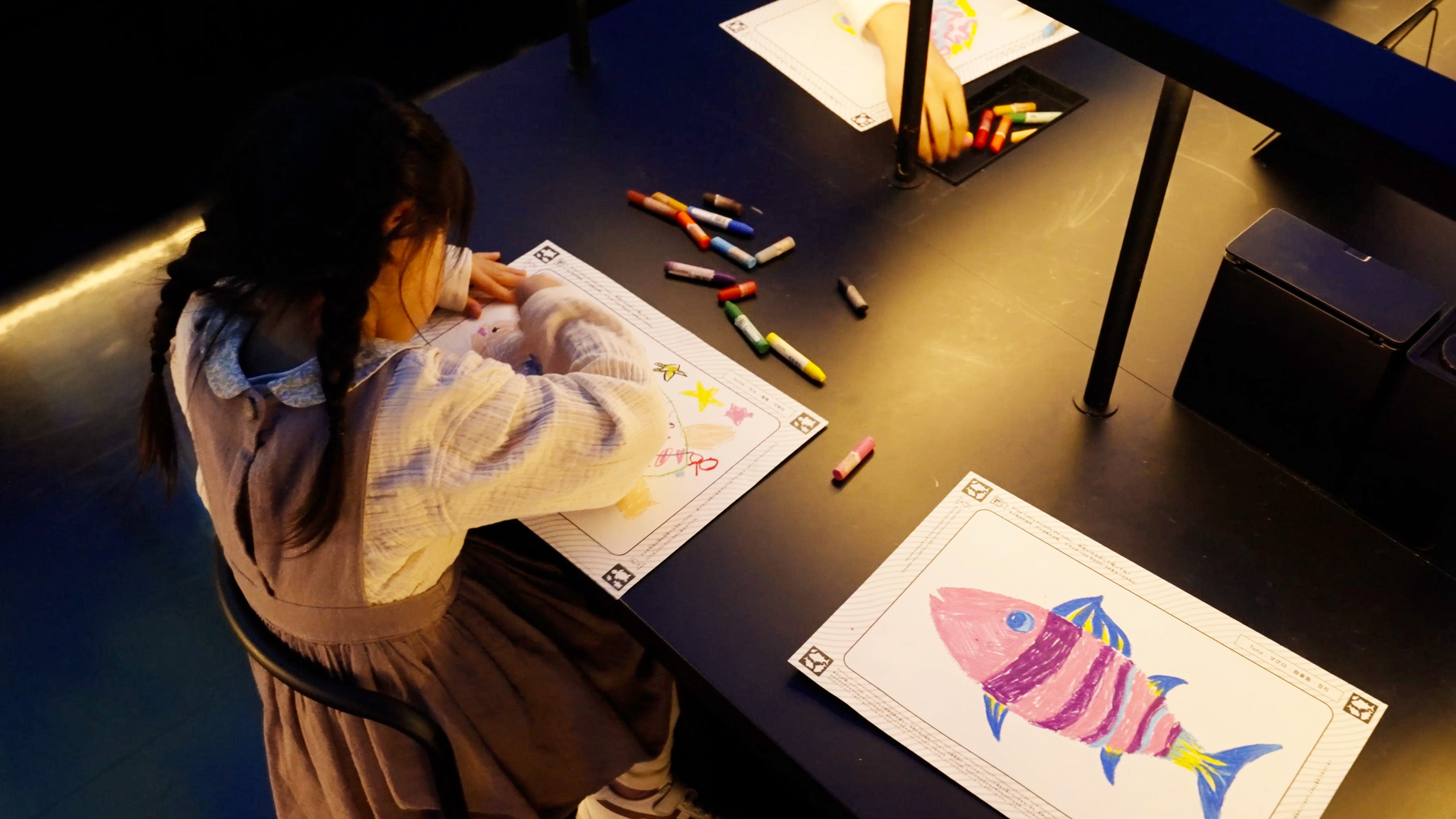 クレヨンを使って、紙に自由に魚の絵を描きます。チームラボ《スケッチオーシャン》©︎ チームラボ