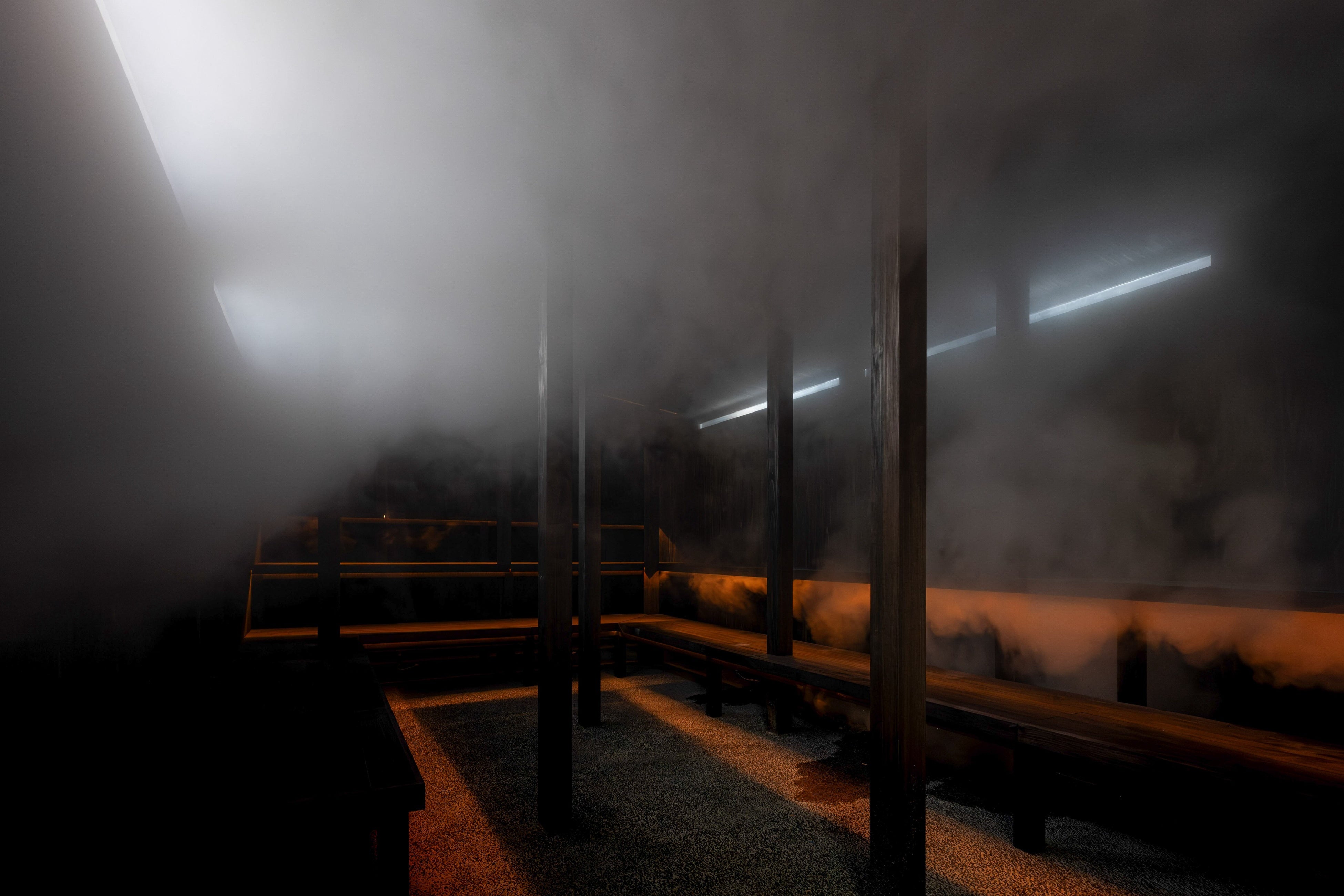 薬草スチームサウナ（男性）：黒を基調としたシンプルなつくり。薬草の蒸気と壁面から差し込む太陽光、夜は最小限のライティングで幻想的な空間を演出しています。